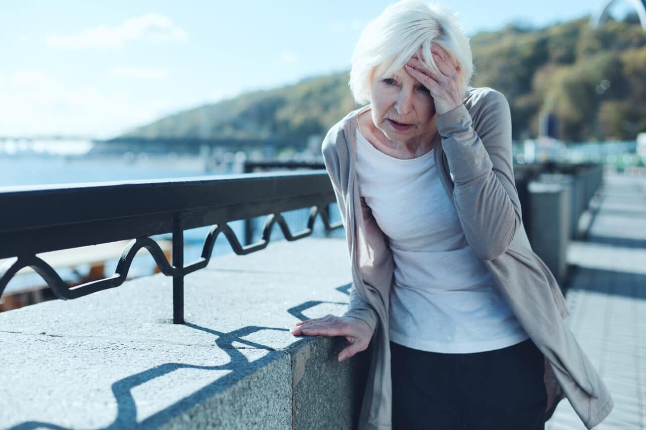 Older woman getting dizzy while out on a walk.